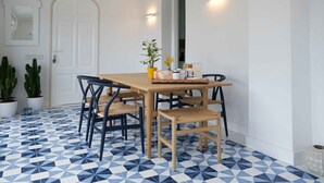 A dining area with a wooden table and chairs, potted plants, and wall-mounted lighting.