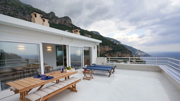 A rooftop terrace with a wooden table, benches, and a ping pong table.