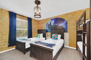 Ein Hotelzimmer mit zwei Betten, Wandgemälde eines Schlosses, Backsteinwänden und einem Kronleuchter.