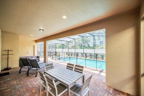 Ein Patio mit Pool, Sitzgelegenheiten im Freien und Blick ins Grüne.
