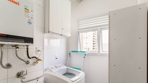 Una lavandería con lavadora, lavabo y ventana con persianas.