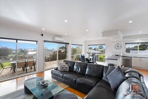 Un salon moderne avec un canapé en cuir, une table basse en verre et un coin repas comprenant une table et des chaises.