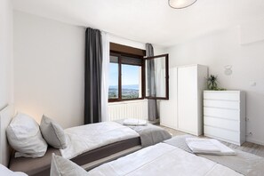 A bedroom with two beds, a window with curtains, a white dresser, and a view of the outdoors. - Apartment Bella Dalia (Solin)