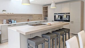 A modern kitchen with a central island, bar stools, a microwave, and a built-in oven.