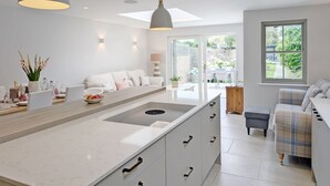 A modern kitchen with a central island, pendant lighting, and a view to a garden.