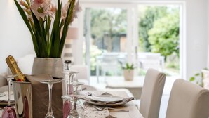 A dining table set with plates, glasses, and a vase of flowers.