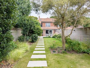 Stroll through the serene garden to a charming home with a brick facade and a living space.