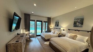 Hotellihuone, jossa on kaksi sänkyä, työpöytä, tuoli, televisio ja näkymä ulos.