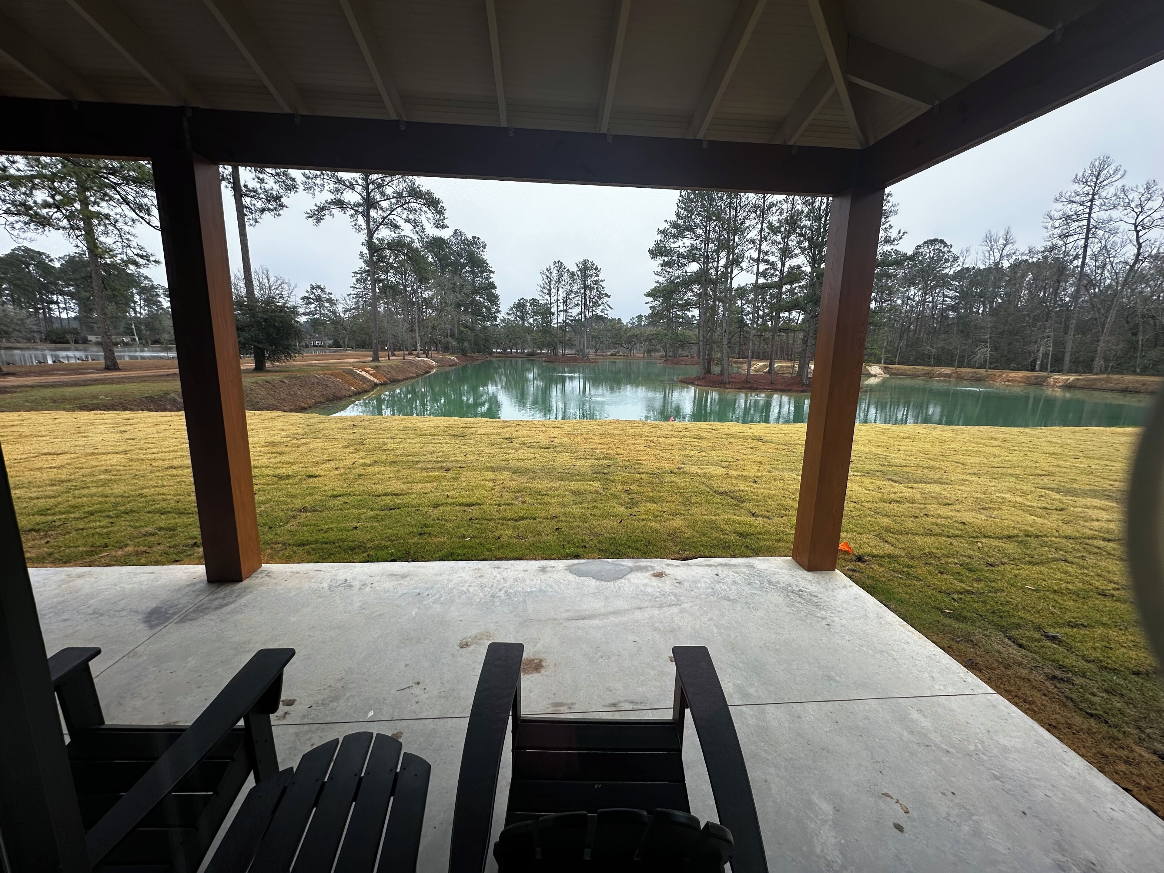 A covered patio area with a view of a pond and surrounding trees.