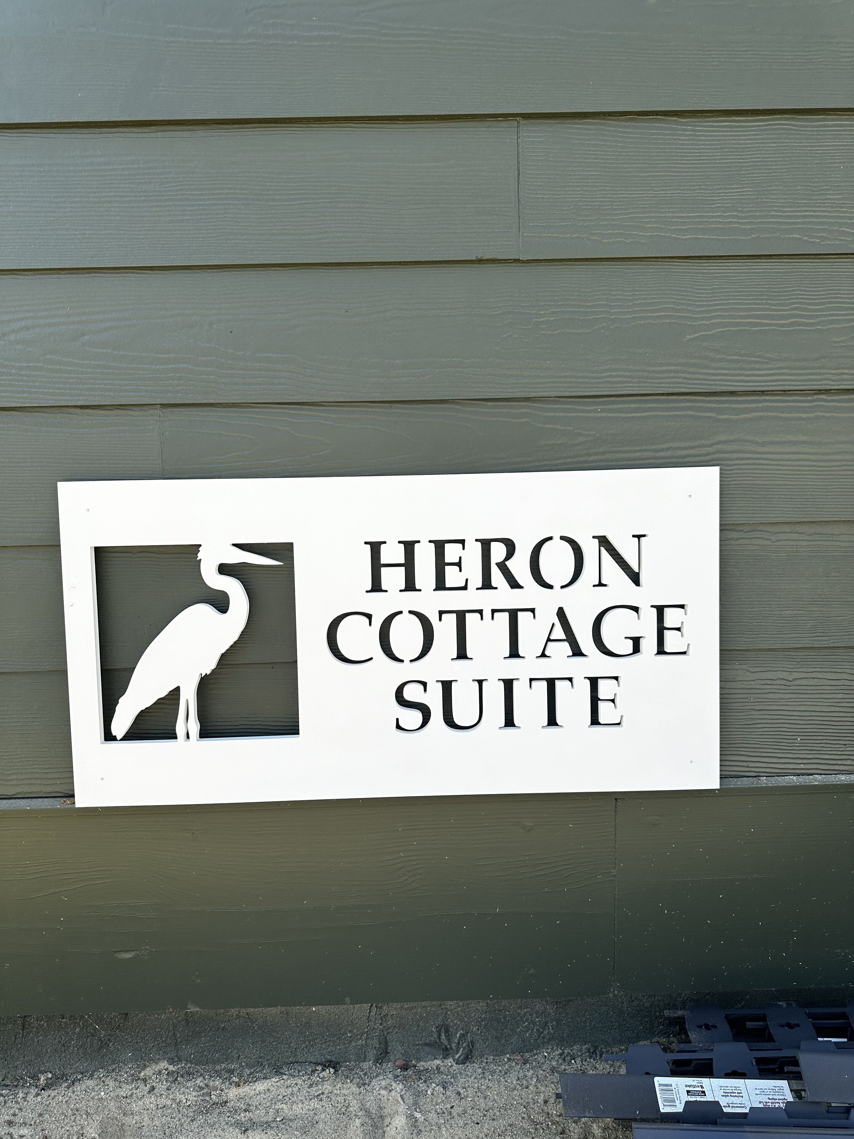 Une enseigne indiquant l’entrée de la suite « Heron Cottage », avec une silhouette stylisée d’oiseau.