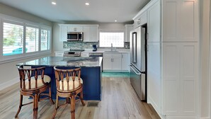 A modern kitchen with white cabinets, a large island, and stainless steel appliances.