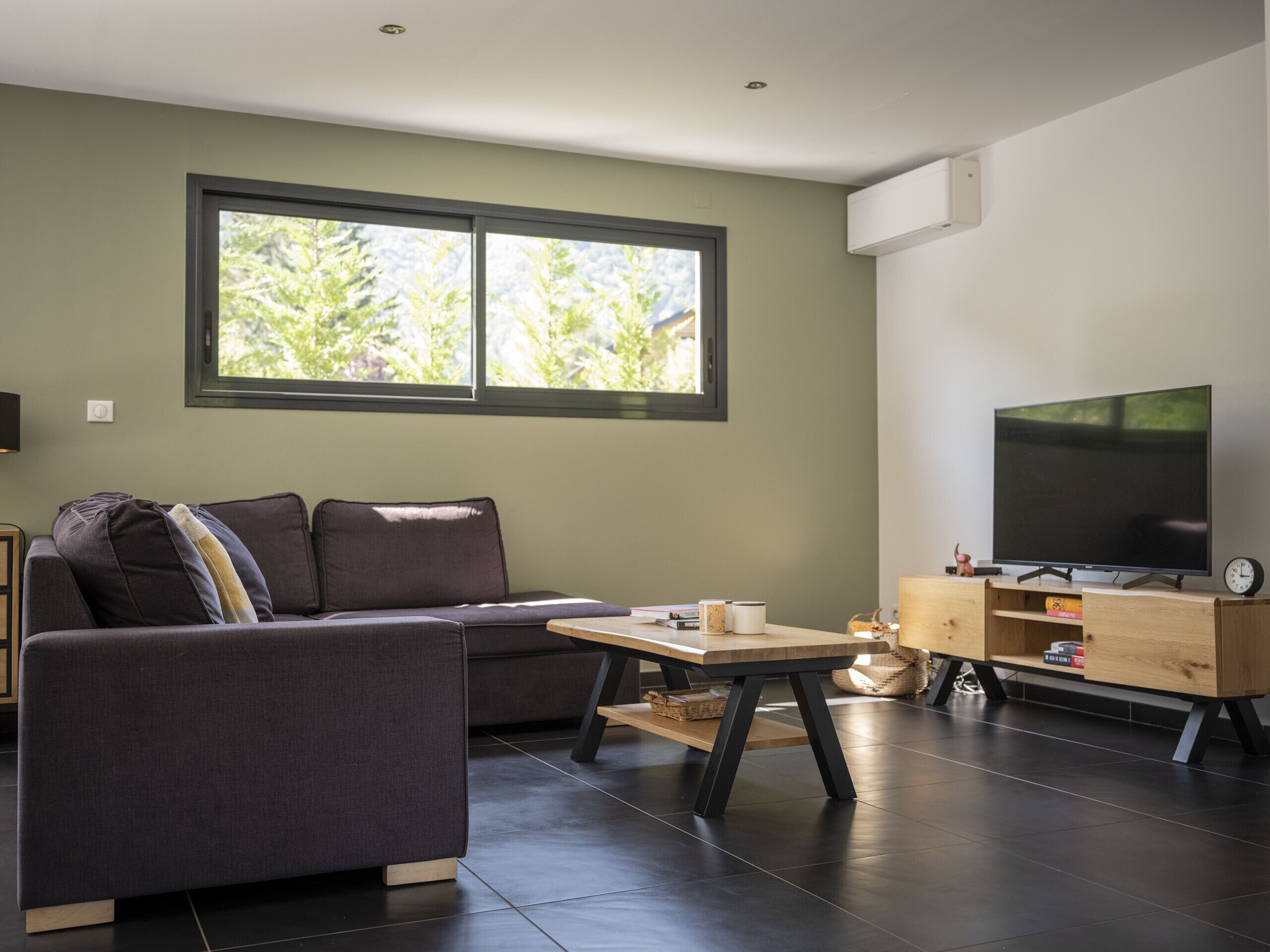 A modern living room with a sofa, a coffee table, and a TV on a wooden stand.