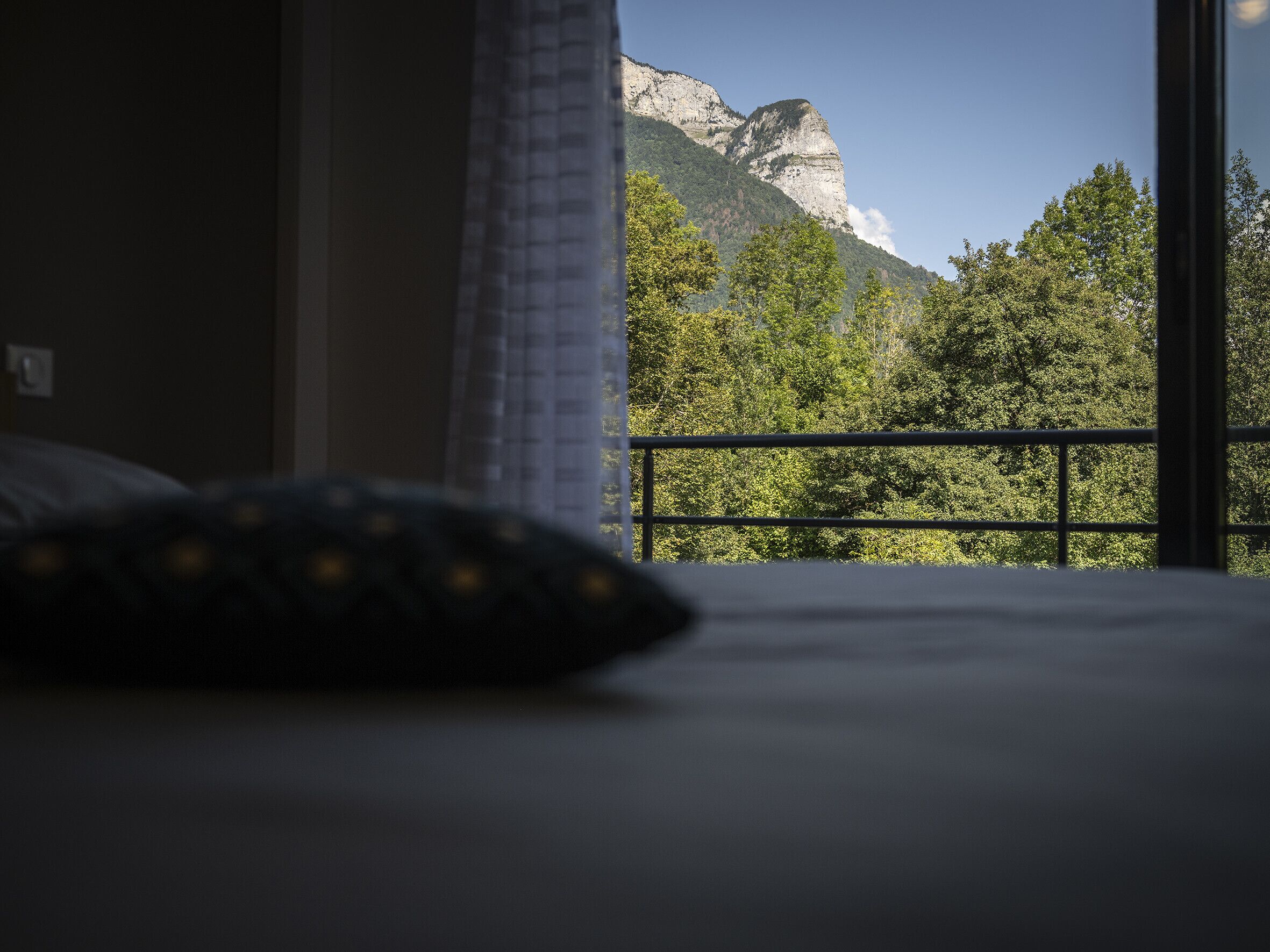 A bedroom with a view of a mountain and trees.