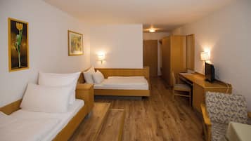 Habitación de hotel con dos camas, un escritorio con computadora, una silla y una mesita pequeña. Hay lámparas de pared y un cuadro en la pared.