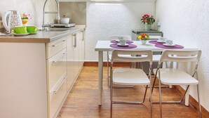Een compacte keuken met dakraam, een eethoek met stoelen en tafel, en een klein raam.