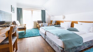 Een hotelkamer met een bed, een bureau, een stoel, een klein tafeltje en een raam met gordijnen.