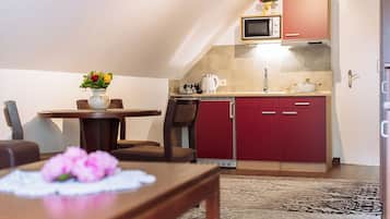 A compact kitchen with a microwave, red cabinets, and a dining area with a table and chairs.