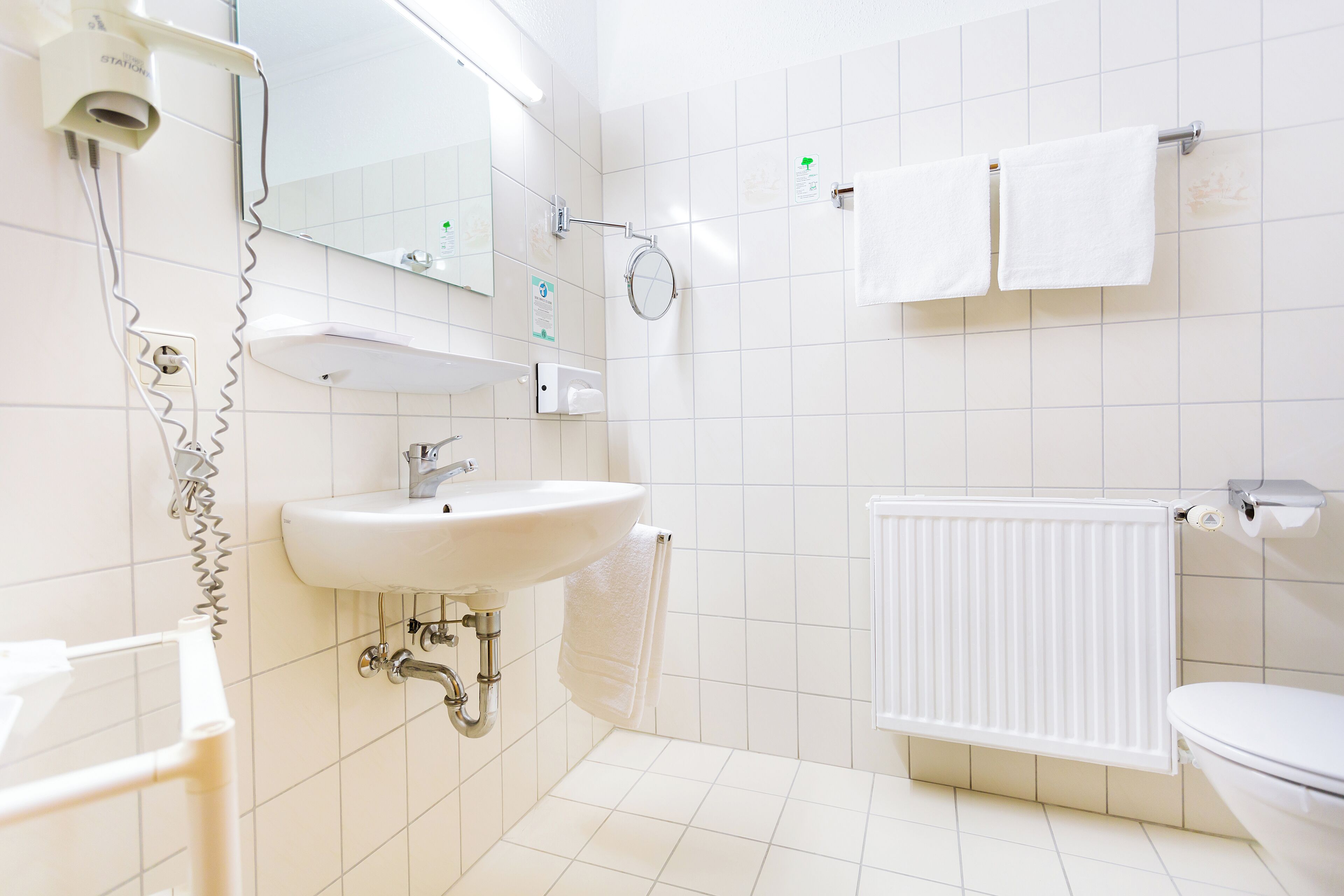 Een badkamer met wastafel, spiegel, handdoekhouder en toilet.