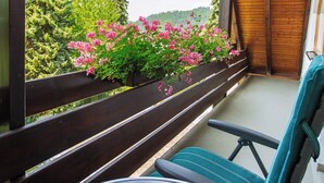 Een balkon met een houten hekwerk, een tafel en een stoel.