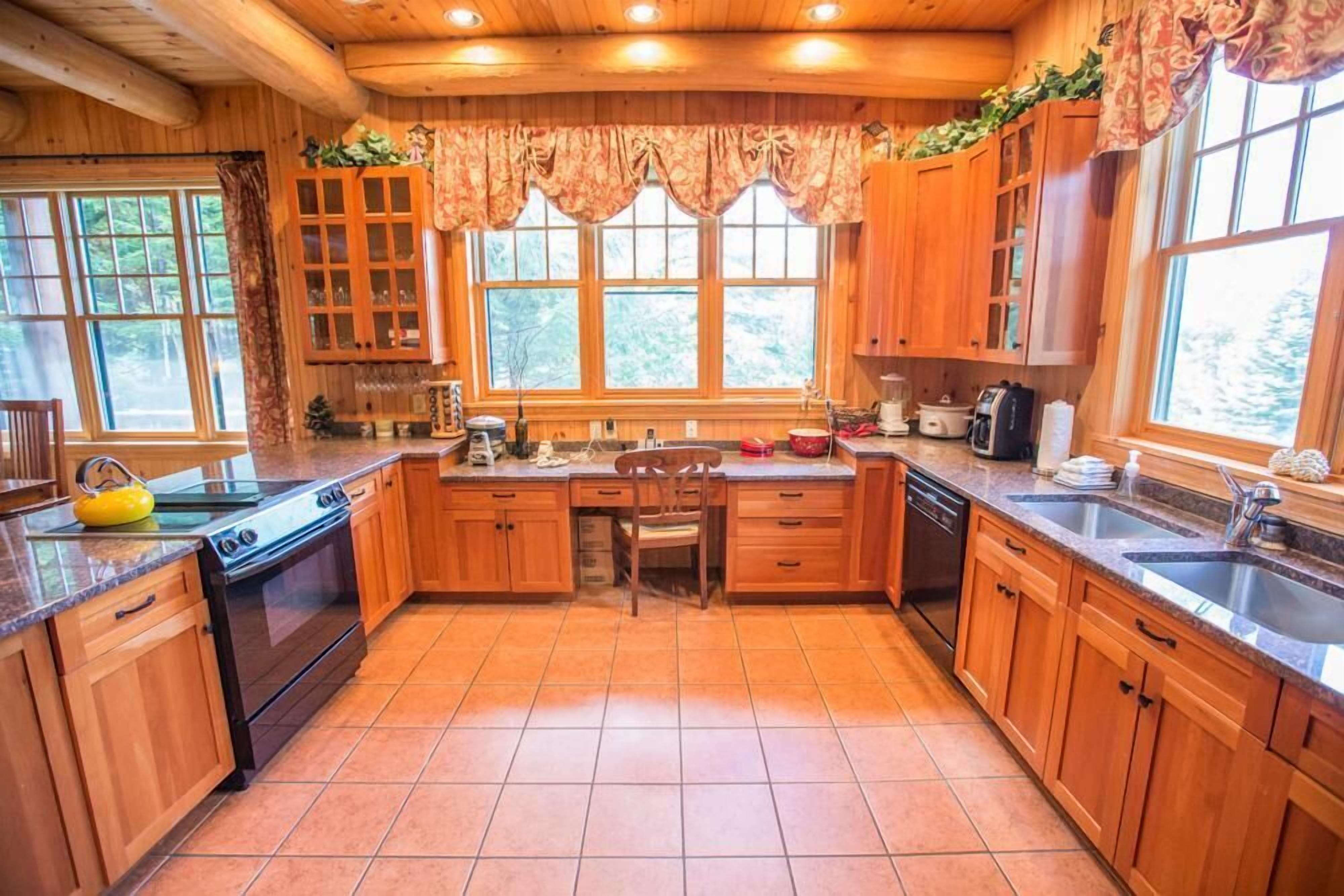 A wooden cabin-style kitchen with a central island, wooden cabinets, and a large window.
