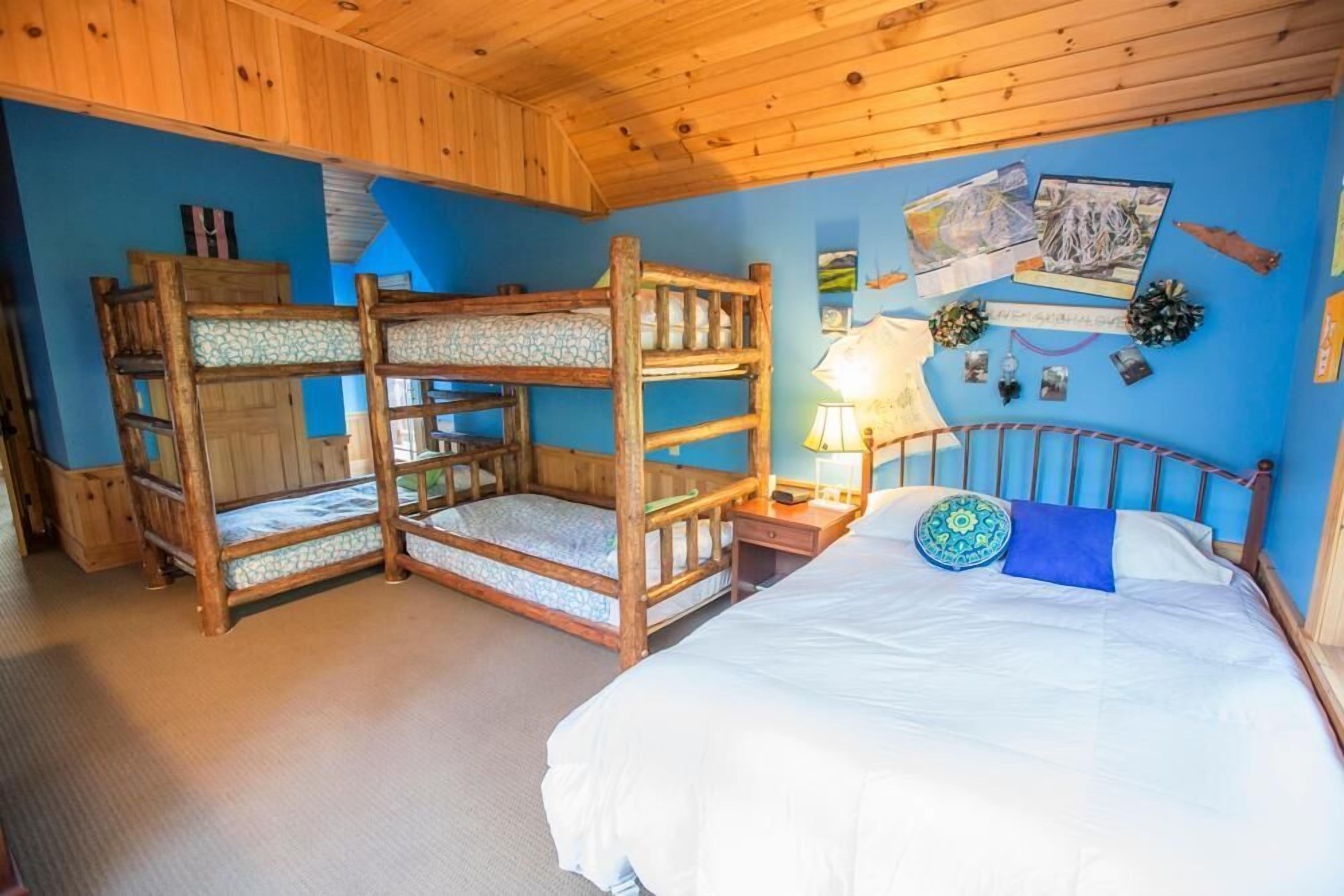 A bunk bed room with a single bed, a nightstand, and wall decorations.