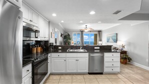 A modern kitchen with white cabinets, stainless steel appliances, and a large island.