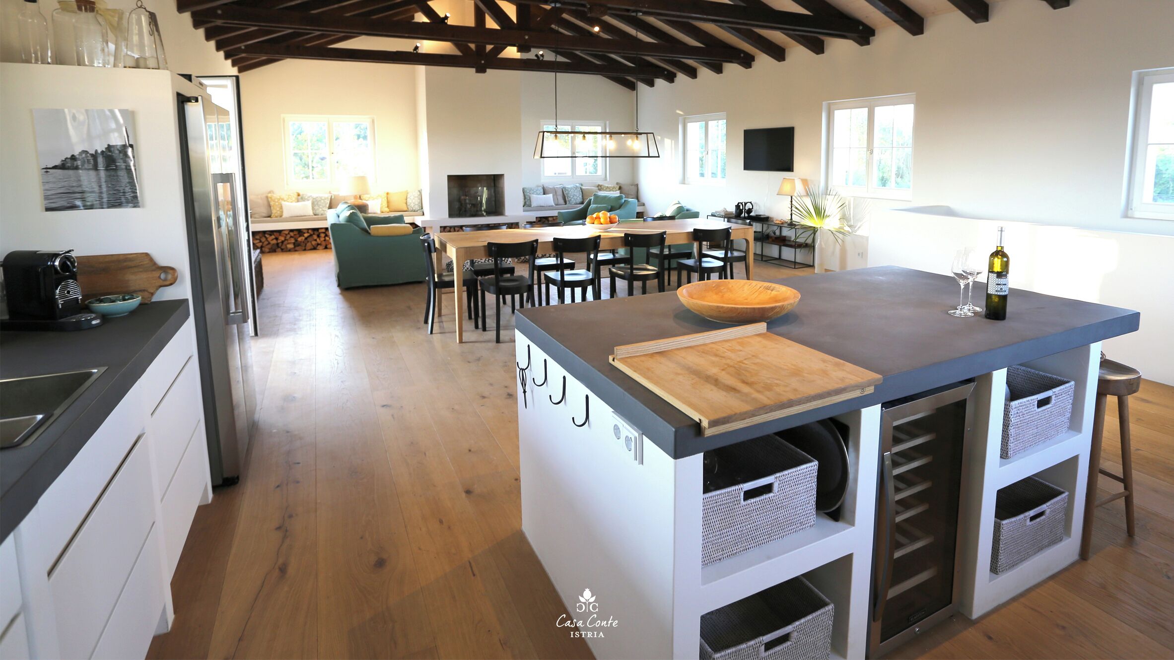 A modern kitchen with a central island, wooden flooring, and built-in appliances.