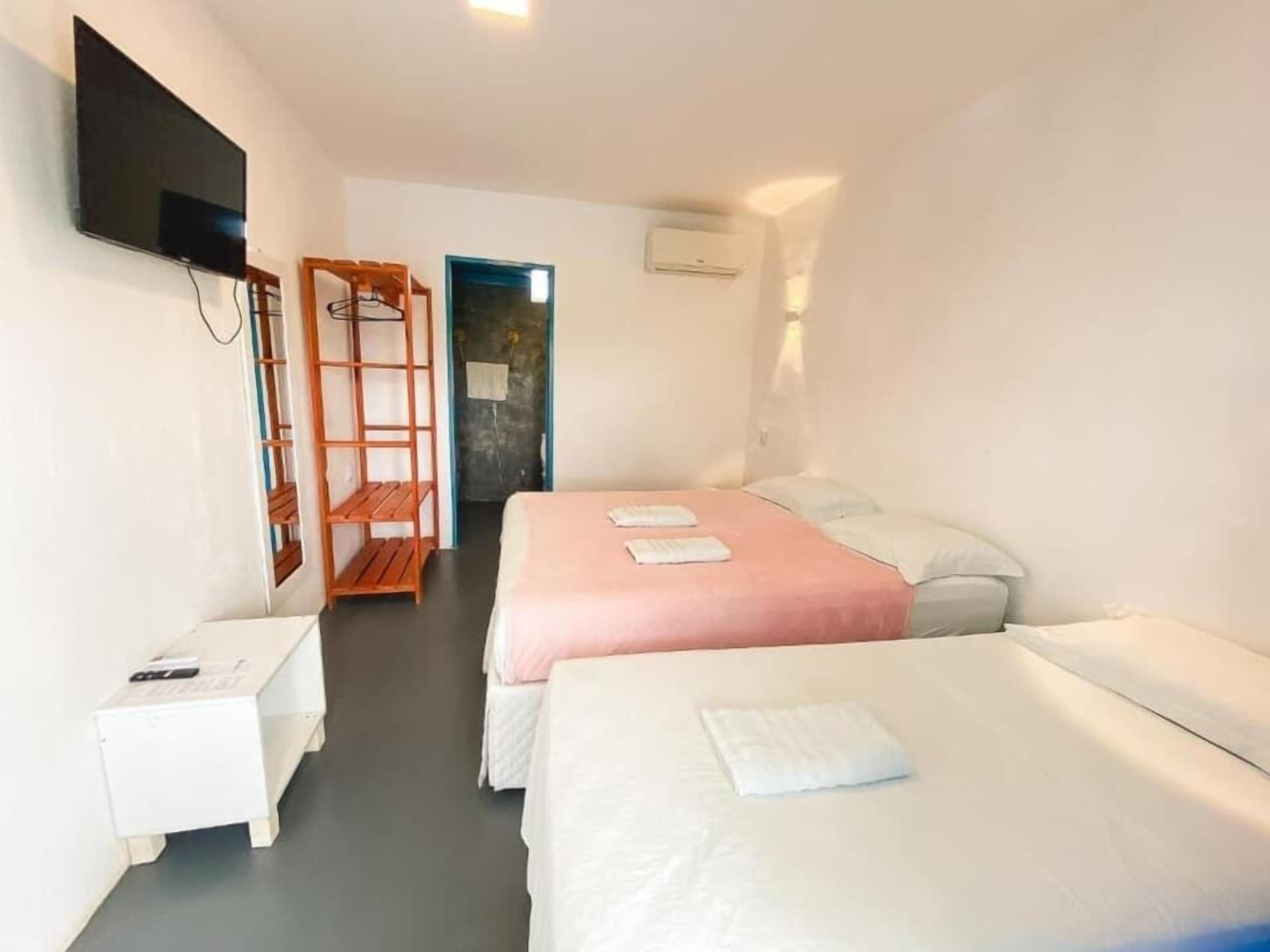 A hotel room with two beds, a TV, a small table, and a wardrobe.