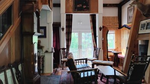 A spacious living area with a high ceiling, wooden staircase, and a large window providing a view of the outdoors. - Mountain, Lake & Babbling Brook Retreat (Newbury)