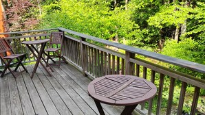 A wooden deck with a round table and two chairs, surrounded by a wooden railing. - Mountain, Lake & Babbling Brook Retreat (Newbury)