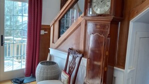 A wooden staircase with a grandfather clock, a cushioned chair, and a view of the outdoors. - Mountain, Lake & Babbling Brook Retreat (Newbury)