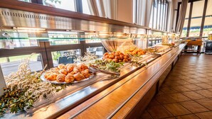 A buffet with various food items, including pastries and salads, displayed on a long counter with glass panels.
