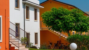 A two-story building with a white and orange facade, a staircase, and bicycles parked outside.