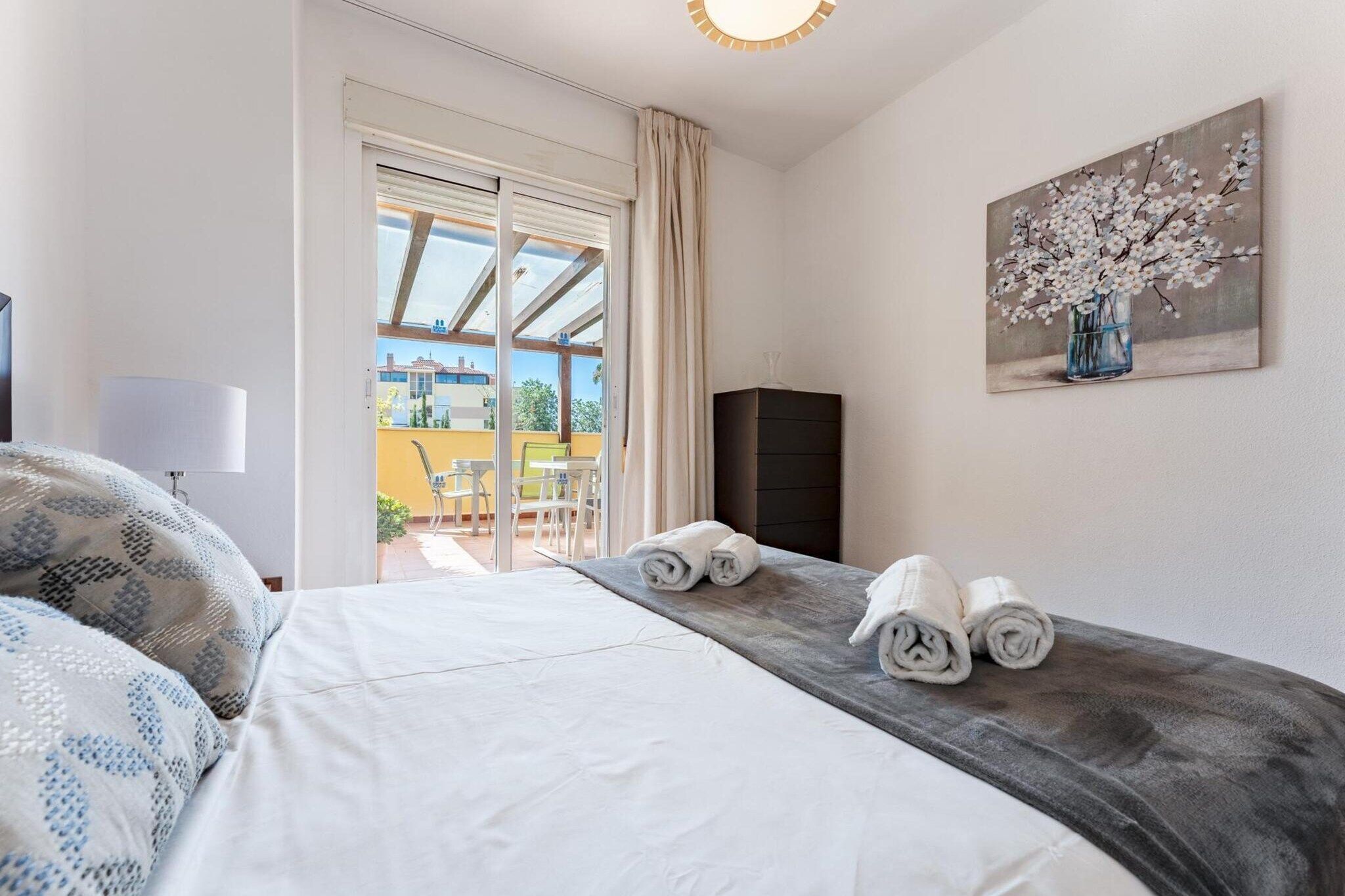 Ein Hotelzimmer mit einem Bett, einem Gemälde, Blick durch das Fenster und einem Stuhl davor.
