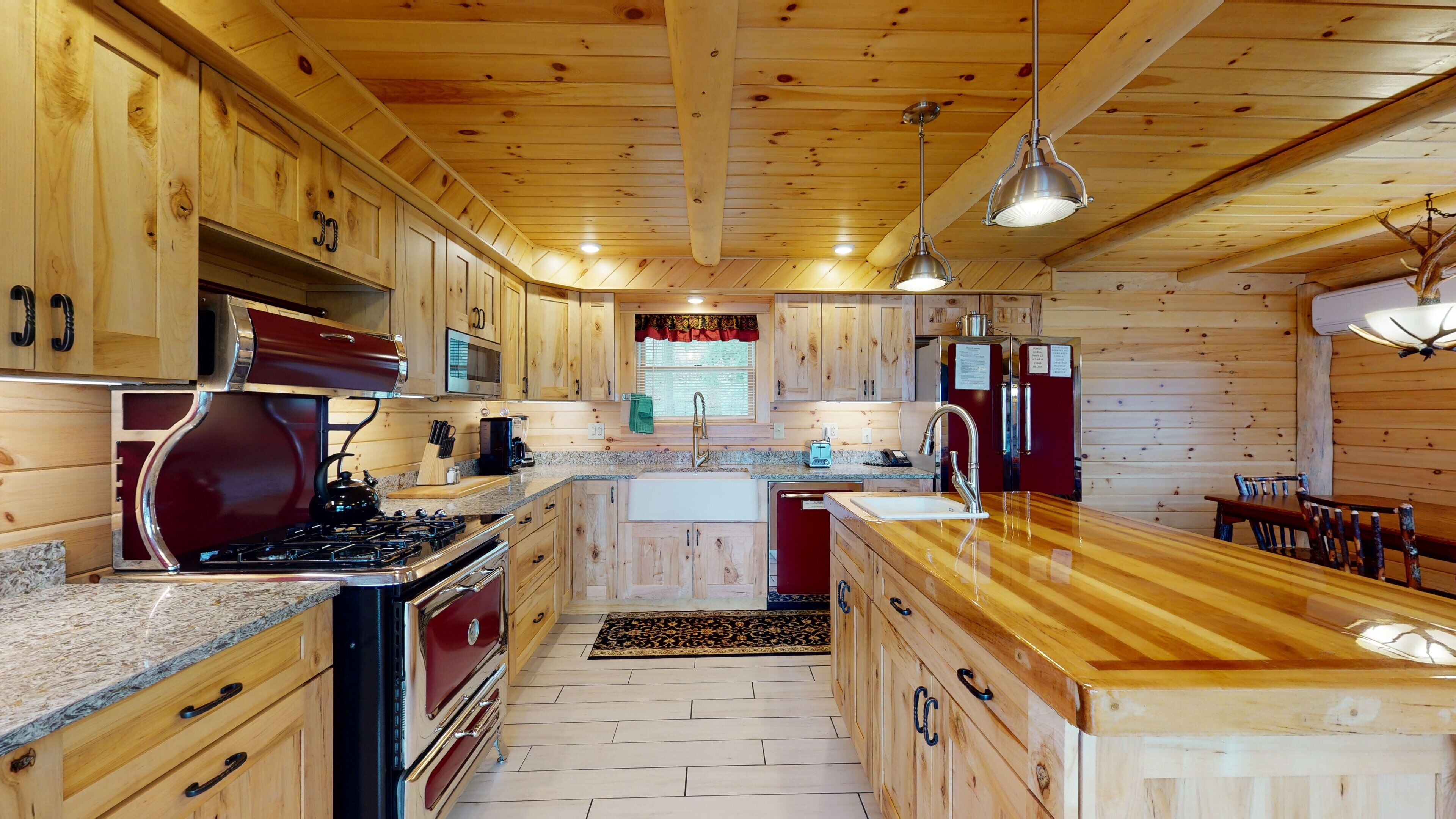 Een houten keuken in blokhutstijl met een centraal eiland, een fornuis en een koelkast.