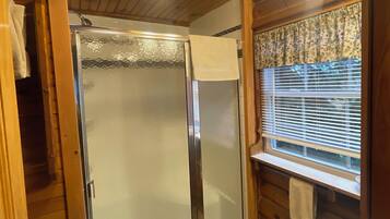 A bathroom with a glass-enclosed shower, a sink, and wooden paneling.