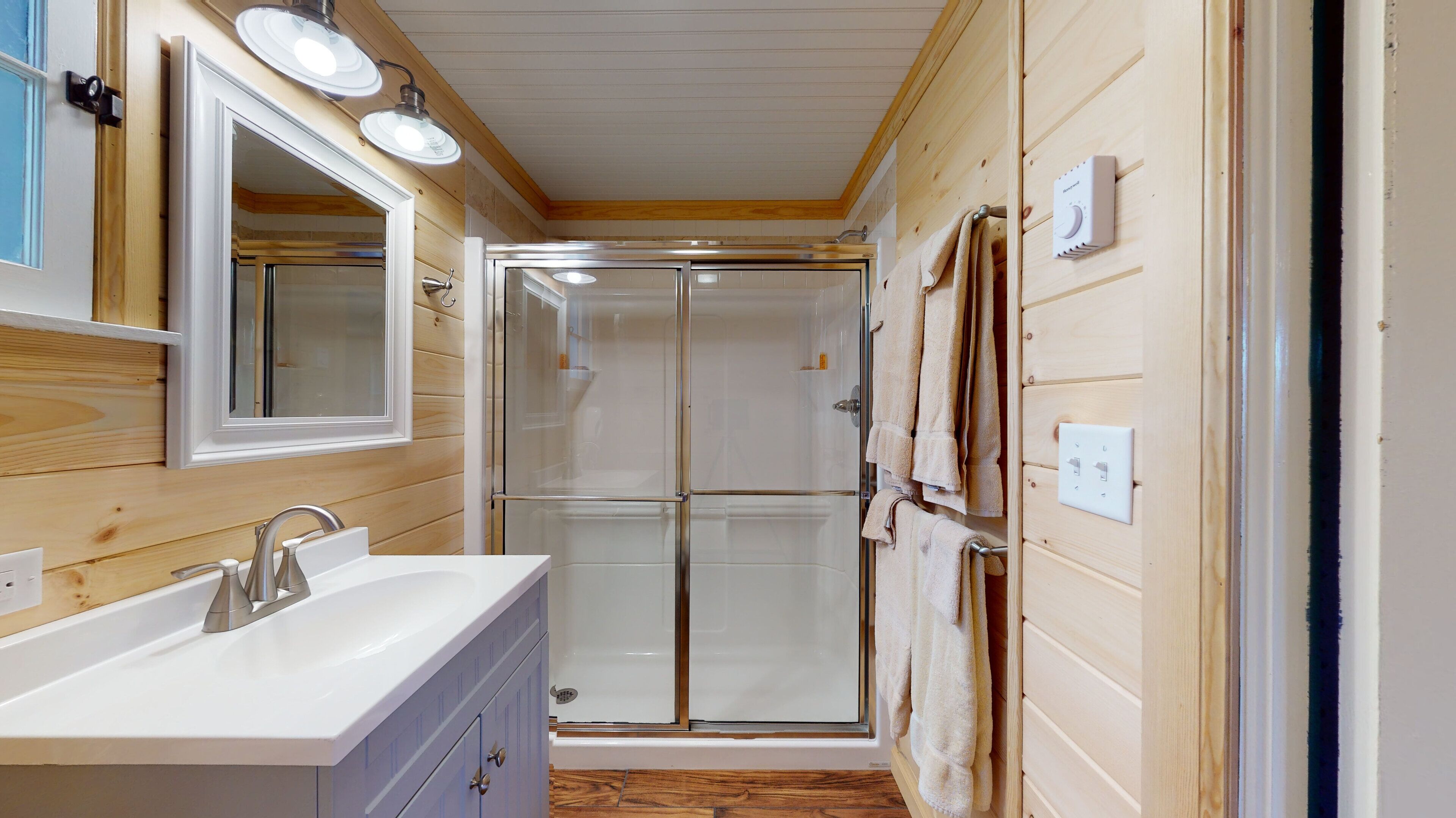 Un interior de madera con un baño que incluye un lavabo, un espejo y un perchero para toallas.