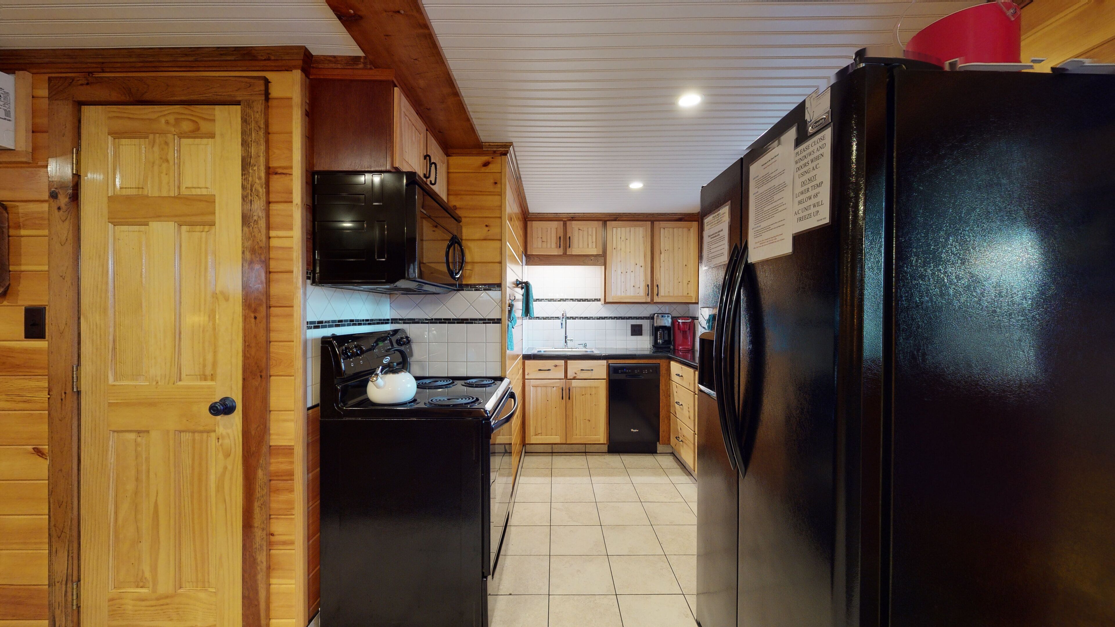 Una cocina con armarios de madera, un refrigerador negro, una estufa y un microondas.