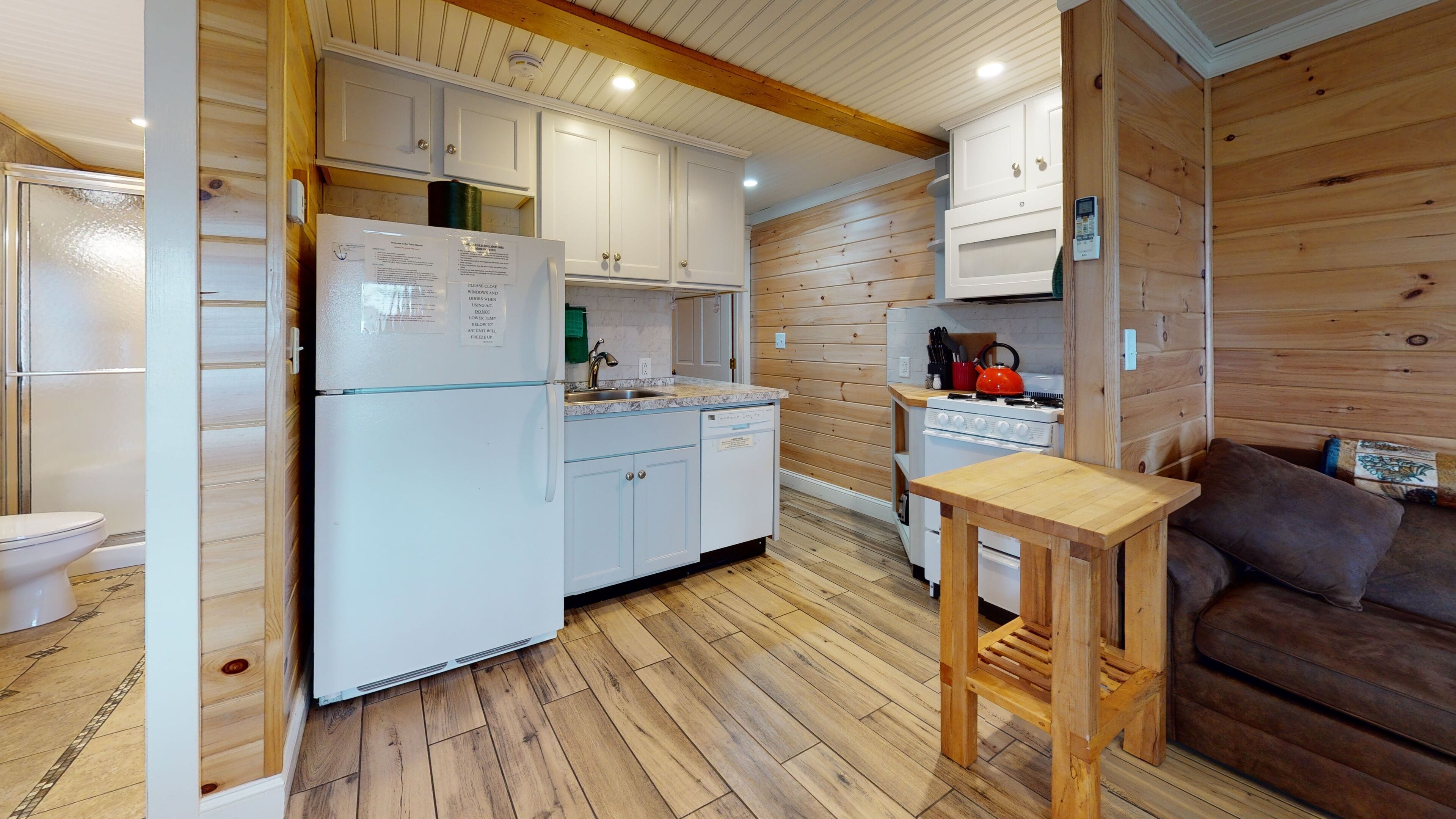 Une cuisine de taille réduite, dotée de meubles de rangement en bois, d’un réfrigérateur, d’un évier et d’une cuisinière.