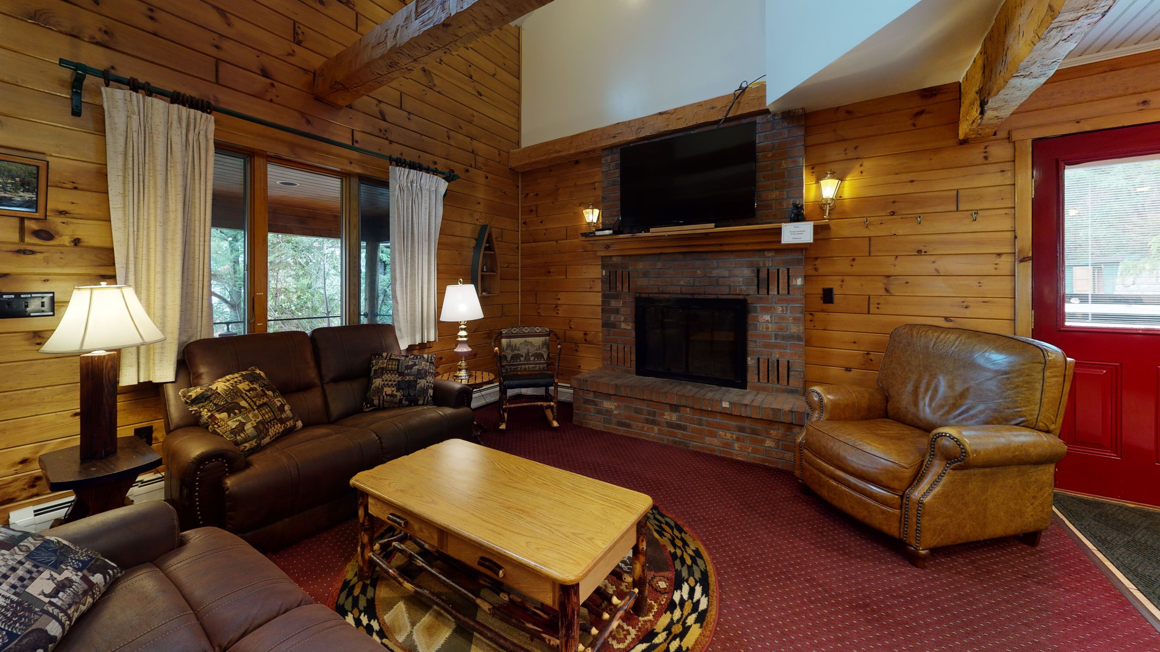 L’intérieur d’un chalet confortable, avec une cheminée, des meubles en cuir et un téléviseur.
