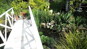 Una terraza de madera que da a un estanque con diversas plantas y rocas.