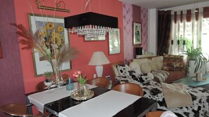 Un comedor con una mesa dispuesta para dos, un sofá con estampado de vaca y una araña colgante.