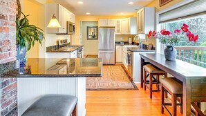 A modern kitchen with granite countertops, white cabinetry, and a large island. - Sequoia Vacation Rental (Milton)
