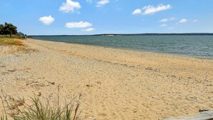 Ein sandiger Strand mit blauem Himmel und ruhigem Wasser.