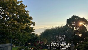 A view of a garden with steps leading down to a seating area, surrounded by trees and a clear sky. - Villa Vica (Musso)