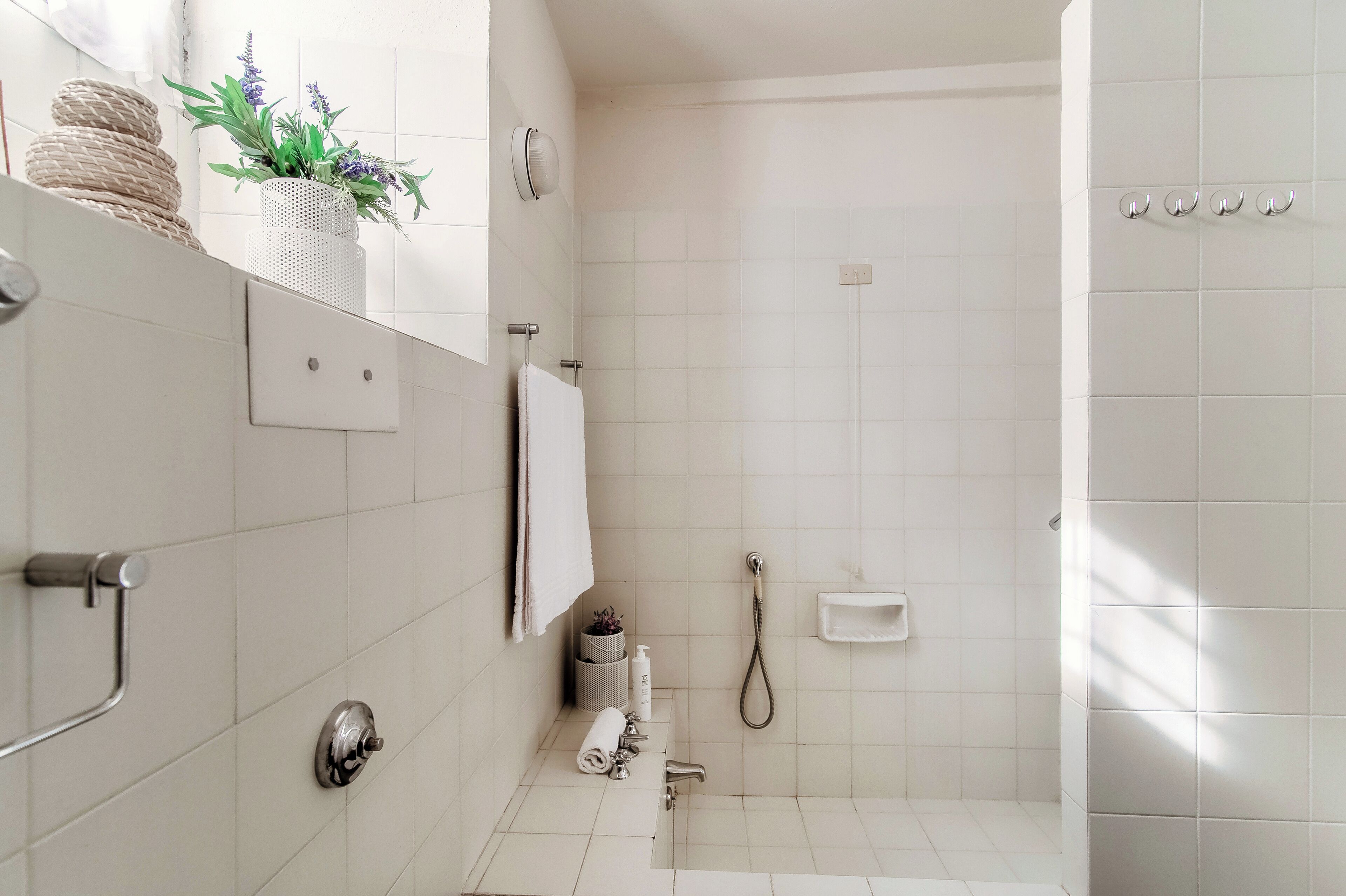 Une salle de bain moderne avec des carreaux blancs, une douche, des toilettes et un lavabo.