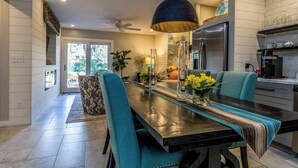 Une cuisine moderne dotée d’un réfrigérateur en acier inoxydable, d’une table à manger avec des chaises et d’un luminaire suspendu.