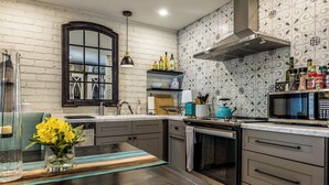 Une cuisine moderne dotée d’un plan de travail foncé, d’un four encastré, d’un four à micro-ondes et d’un revêtement mural décoratif à motifs géométriques.