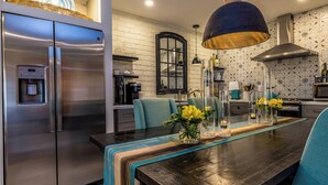 Une cuisine moderne équipée d’appareils électroménagers en acier inoxydable, une table à manger avec des chaises et des vases décoratifs.