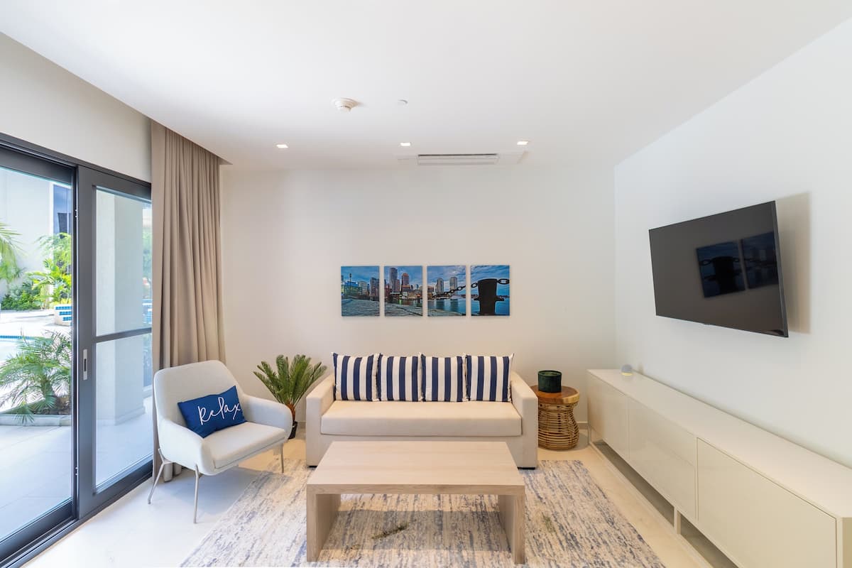 Ein modernes Wohnzimmer mit einer Couch, einem Sessel, einem Couchtisch und einem an der Wand befestigten Fernseher.